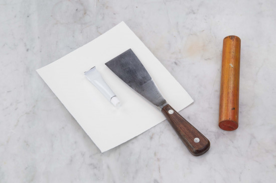 Pull the paper carefully out of the tube. Flatten the end of the tube again, fold the metal (with help of a palette knife or a spatula) to close the tube.